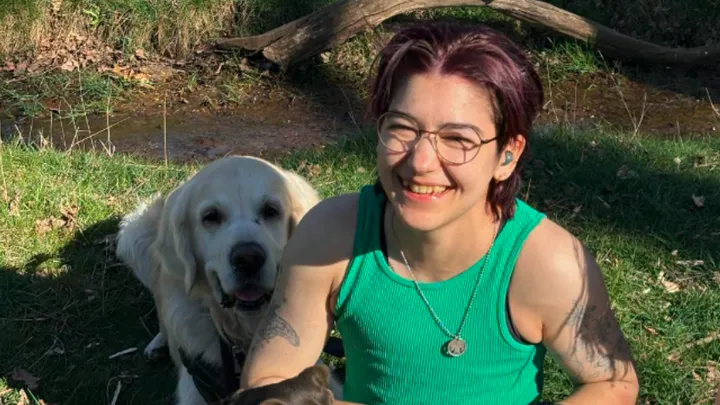 A photo of Jay sitting next to a dog on some grass